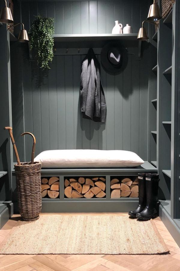 Dark green entryway storage bench from @viviennecutler featuring ikea mud room ideas with firewood compartments below.