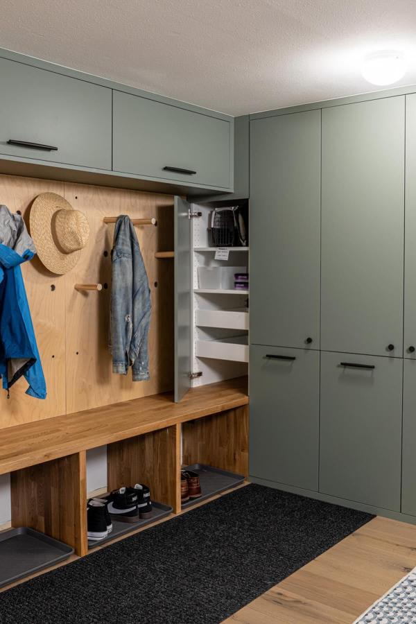 Sage green painted cabinet system from @braveelement with natural wood bench and hidden storage solutions.