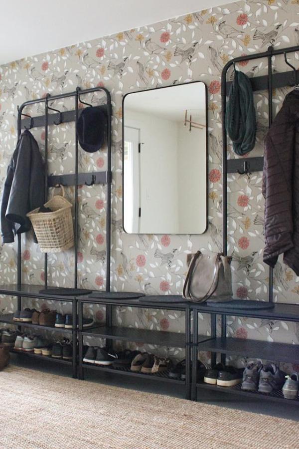 Black metal coat rack system from @pvhomestaging with floral wallpaper and organized shoe storage below.