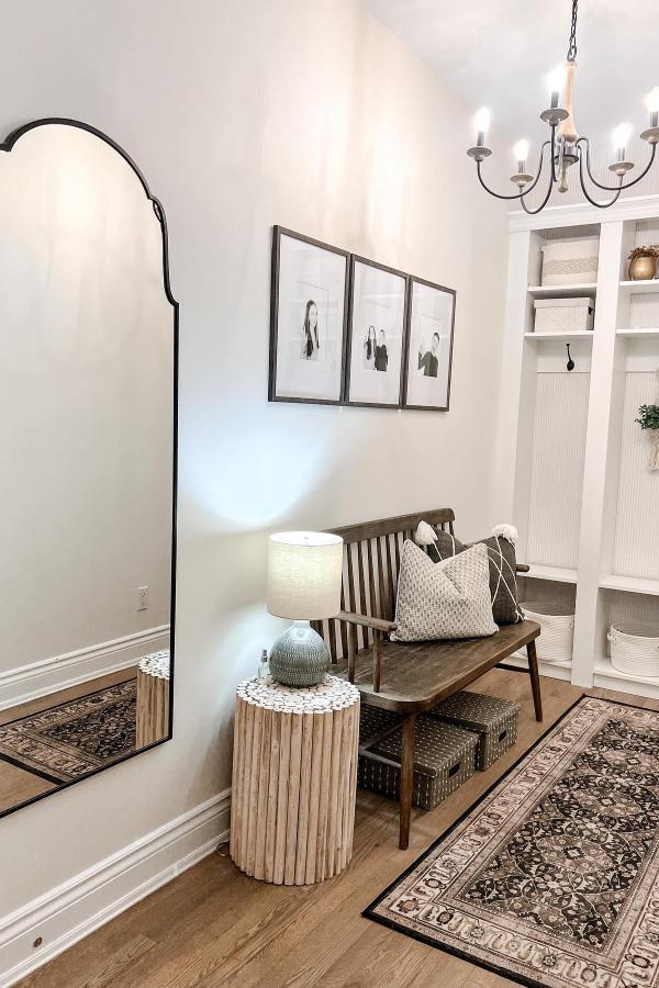 Neutral mudroom entryway from @katrinalgallagher featuring built-in storage cubbies and wooden bench with woven baskets.