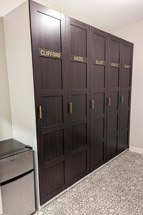 Dark wood locker-style wardrobes from @unofficialtastetester. Personalized brass nameplates on each compartment door.