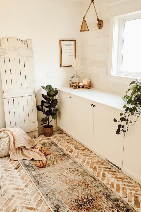 Rustic mudroom storage from @talk_repurposed featuring white cabinets and brick flooring.