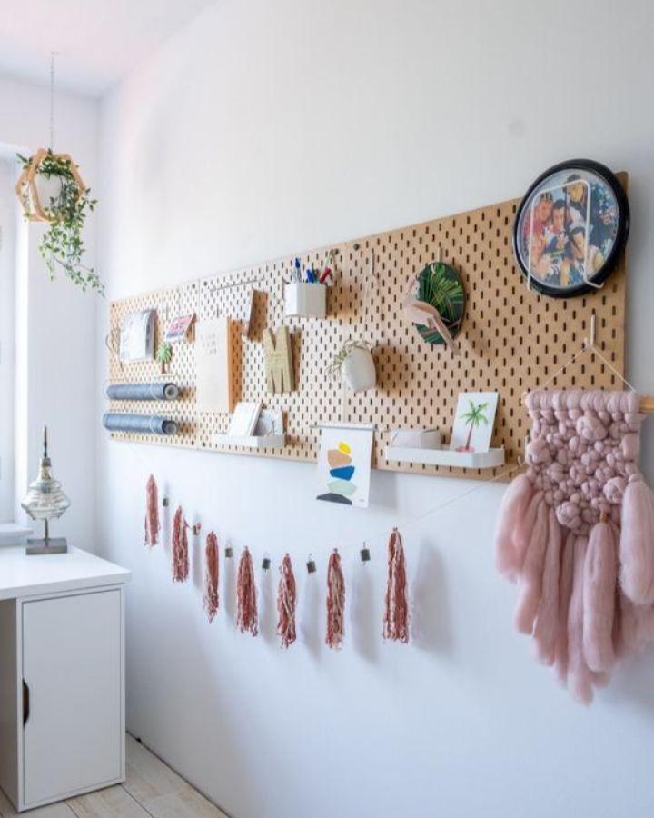 Boho workspace pegboard from Een Goed Verhaal. Pink tassels hang below natural wood storage board.