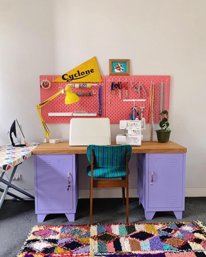 Coral-pink painted pegboard craft station from @lindseyjanehoward. Transformed workspace with colorful storage solution.