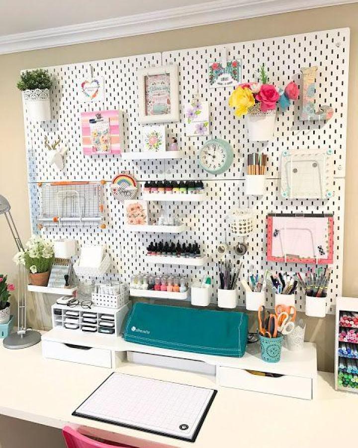 Large white pegboard wall display showcasing ikea skadis pegboard hacks & ideas from The Crazy Craft Lady. Colorful craft supplies organized with various accessories.