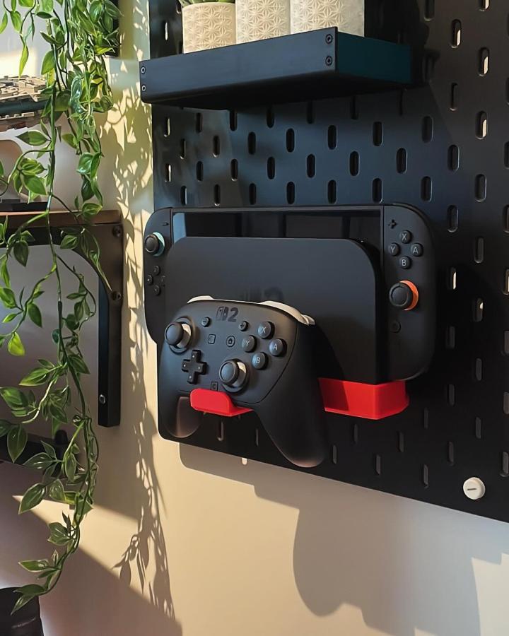 Black pegboard gaming station from @foxwood.creative. Nintendo Switch dock with red controller holders mounted on wall.