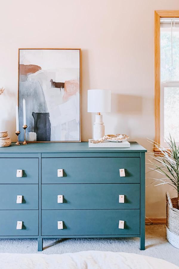 Sage green painted bedroom dresser from @thrifty_abode. White square knobs and abstract art styling complete the look.