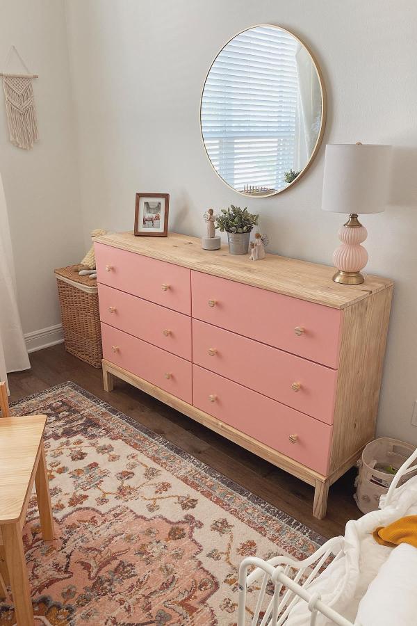 Coral pink and natural wood dresser from @itsjulisworld styled with round mirror and decorative accessories.