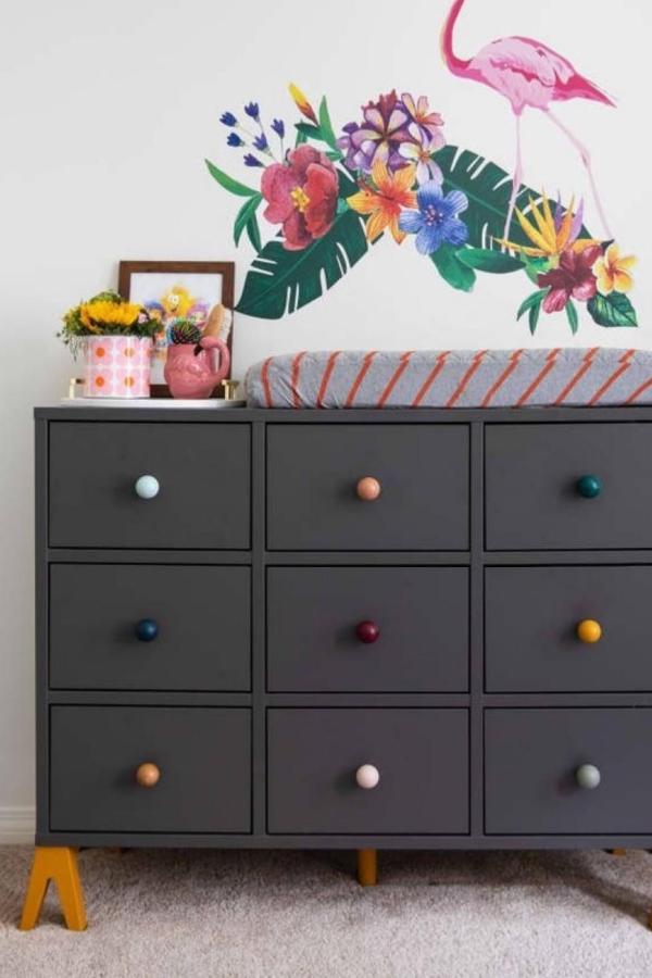 Dark gray painted dresser from @rteriorstudio with vibrant rainbow knobs and tropical wall decals.