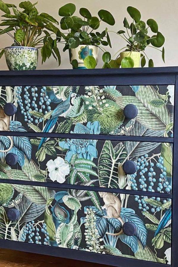 Navy blue tropical dresser from @pillarboxblue featuring botanical wallpaper with green leaves and blue berries.