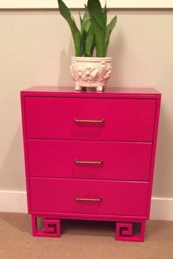 Bright pink dresser from @julie_simpleredesign with decorative geometric Greek key base cutouts and brass handles.