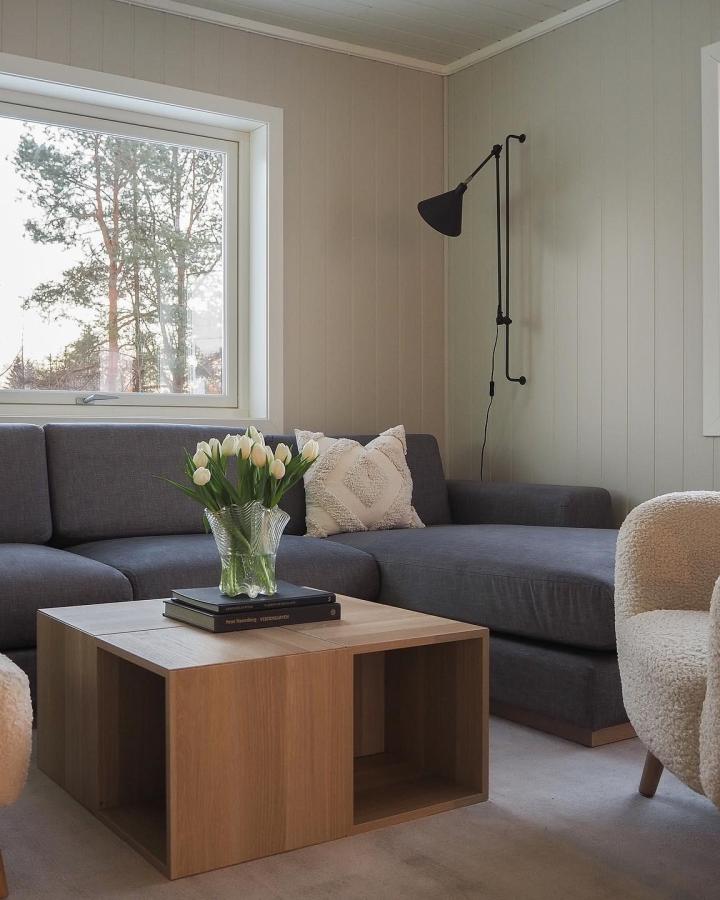 Wooden cube coffee table with open storage compartment from @grimerudvegen. Modern living room styling with books and flowers.