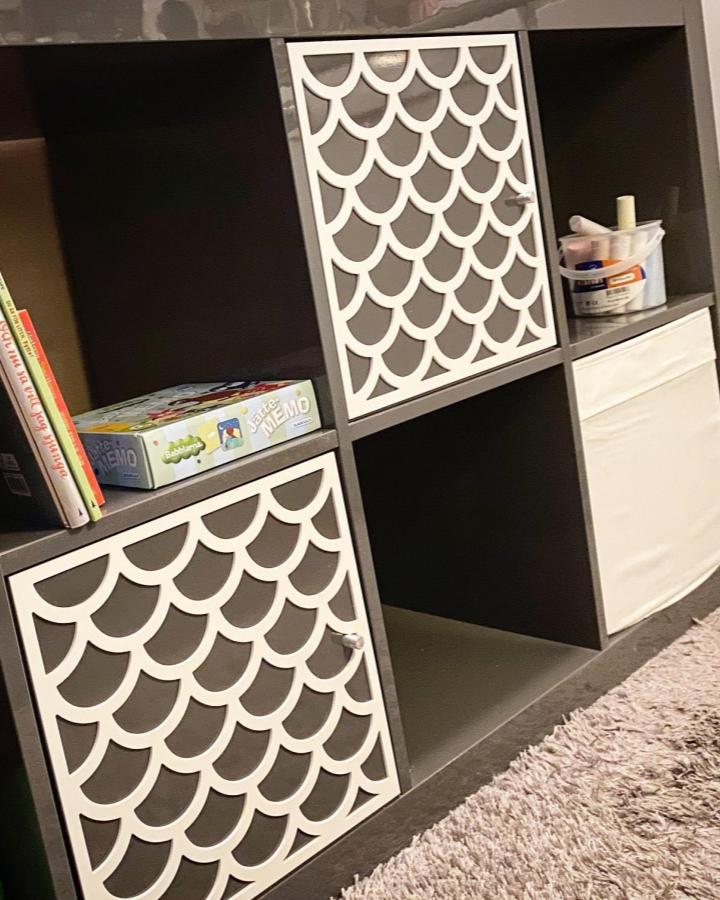 White scalloped door panels on dark cube storage from @frontcover.se. Custom decorative fronts create sophisticated hidden storage.