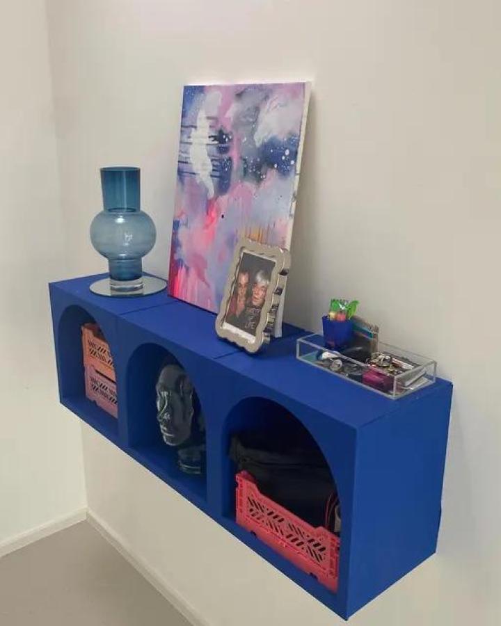Bright blue painted storage unit from @guippdecor. Displaying books, decor items, and colorful accessories in open cubes.