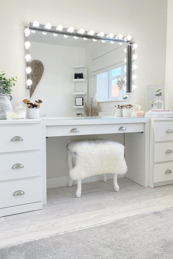 White vanity setup from @angels_home_ featuring mirror with surrounding LED bulb lights for glamorous styling.