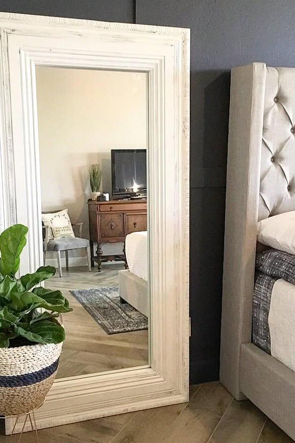 Large white-framed mirror transformation from @houseofrumours. Chunky molding creates expensive custom look in bedroom corner.