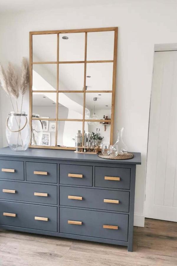 Wooden grid mirror mounted above blue-gray dresser from @making_the_mairesfield_home. Creates window-like appearance with multiple reflective sections.