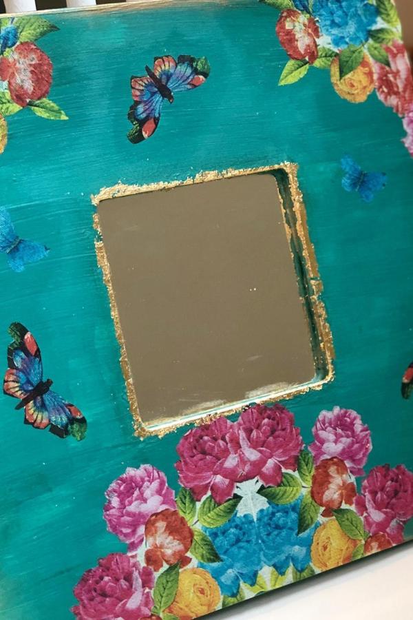Colorful decoupage mirror craft from @paperscissorstitch. Turquoise background with pink flowers and blue butterflies.