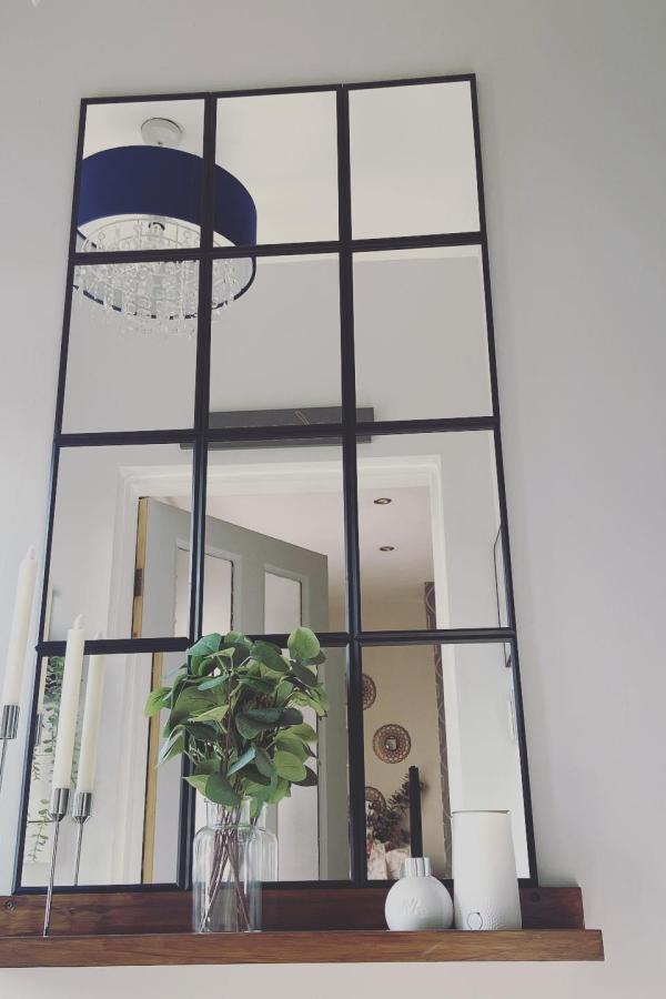 Black grid-framed wall mirror showcasing ikea mirror hacks & ideas from @familyeverafteruk. Industrial window-style transformation with decorative shelf styling.