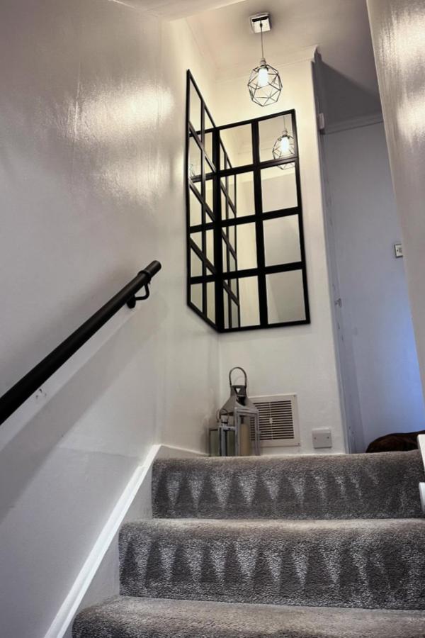 Modern black grid mirror installation from @homewiththelawsons. Creates dramatic wall feature in neutral stairway space.