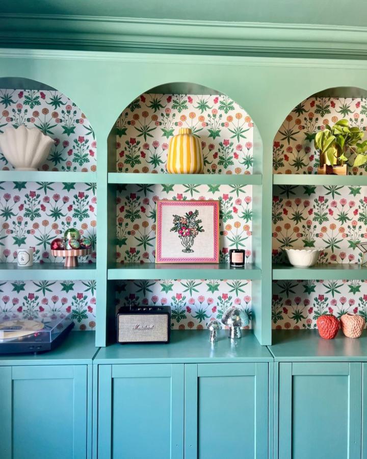 Mint green arched bookcase with botanical floral wallpaper backing from @homeofcharl showcasing colorful styling.