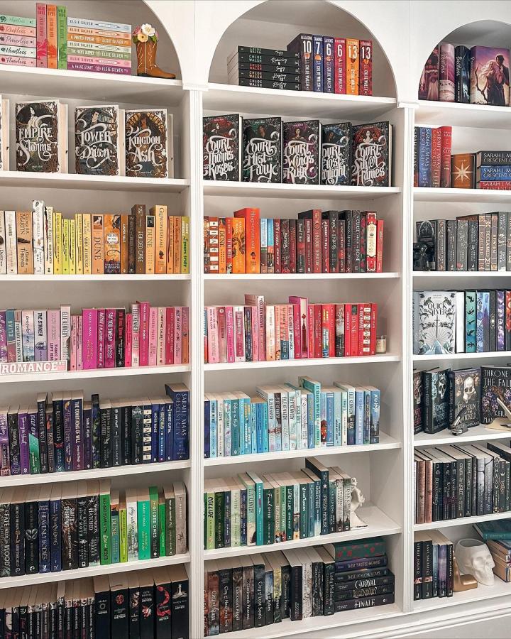 White bookcase displaying color-organized books showcasing creative ikea arched bookcase hacks & ideas from @booksreadbyriss.