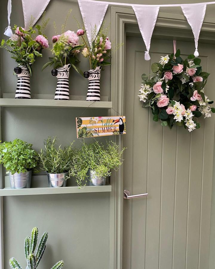 Striped vases and herb buckets from @thegingerhareofyorkshire. White shelving displays seasonal flowers and plants beautifully.