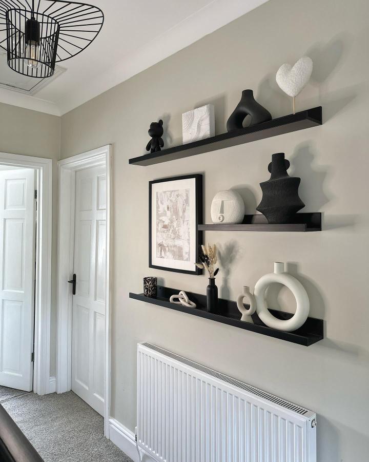 Monochrome hallway display from @homewithgeorgia_. Black floating shelves showcase white ceramic vases and sculptural decorative objects.