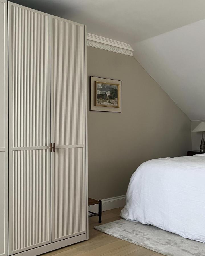 Fluted panel wardrobe doors in neutral bedroom from @foxstow with natural wood floors and sloped ceiling