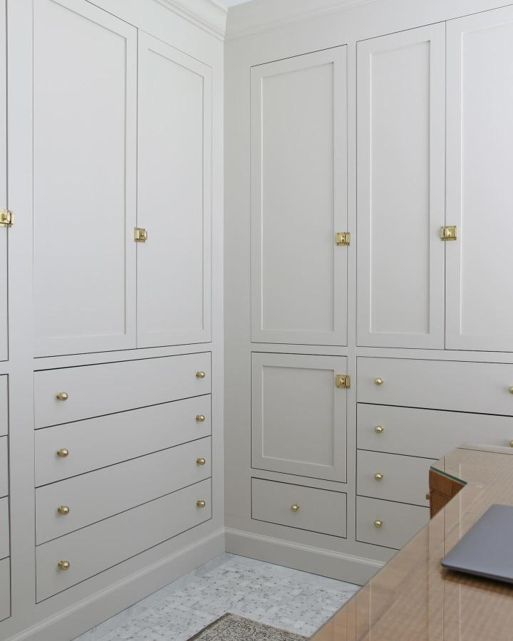 Pale gray built-in wardrobe with brass knobs and drawer storage from @stefanasilber. Shaker panel detailing throughout