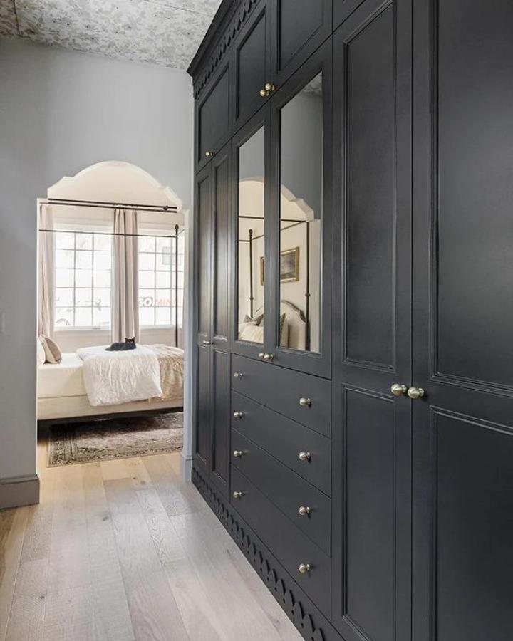 Charcoal mirrored wardrobe with brass hardware in bedroom hallway from Jenna Sue Design. Architectural trim detail at base.