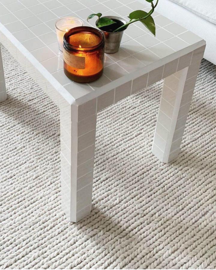 White tiled side table from @rightpricetiles featuring ceramic mosaic surface transformation with candle and plant styling.