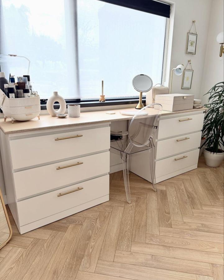 Modern white vanity setup from @thesavvy.home. Two Malm drawer units with wood countertop and acrylic chair.