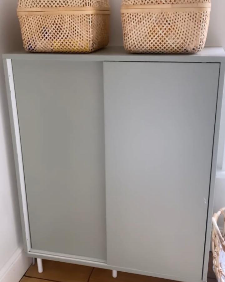 Sage green Ikea Mackapar cabinet from @littlebluenestbaby with woven baskets and white legs in nursery.