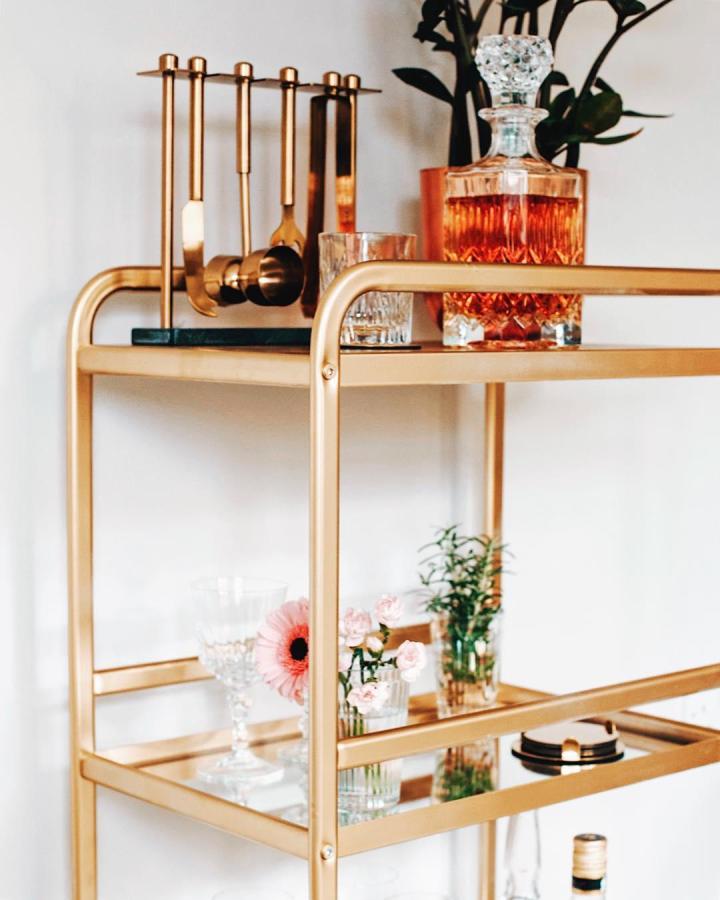 Gold-framed Sunnersta bar cart from @iamlila. Styled with copper tools and crystal glassware.