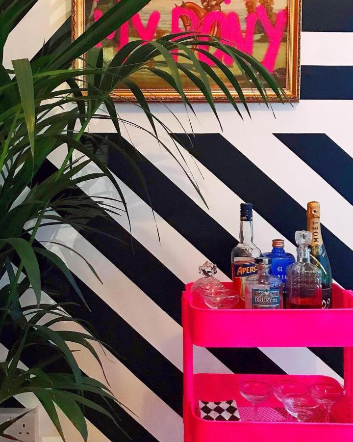 Hot pink Ikea Raskog bar cart from @maisieviolet_rees with striped wall backdrop and glassware display.
