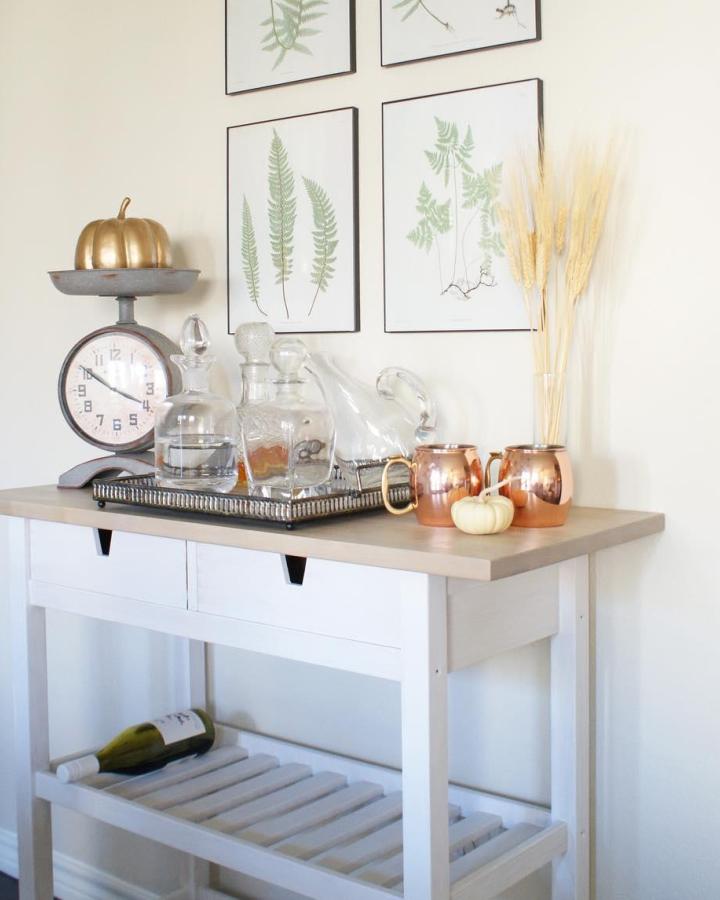 Autumn-styled Ikea Forhoja cart from @hayleywithbooks with ikea bar cart hacks & ideas featuring copper mugs and pumpkins.