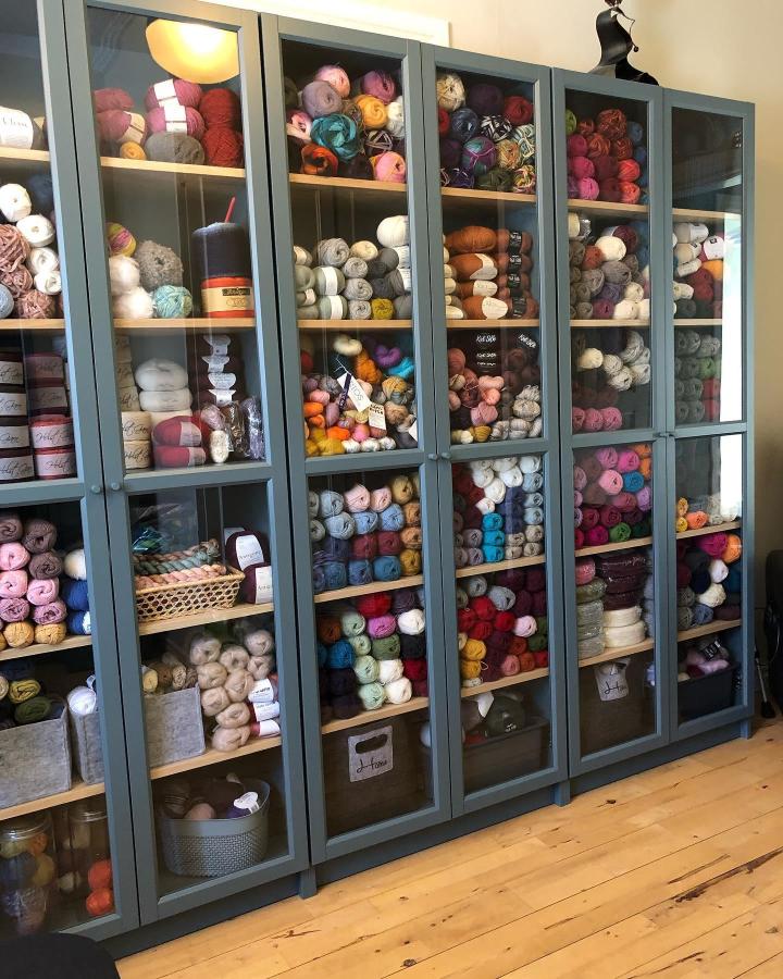Slate-blue glass door Billy bookcases from @annmariahelena. Organized yarn storage with colorful skeins visible.