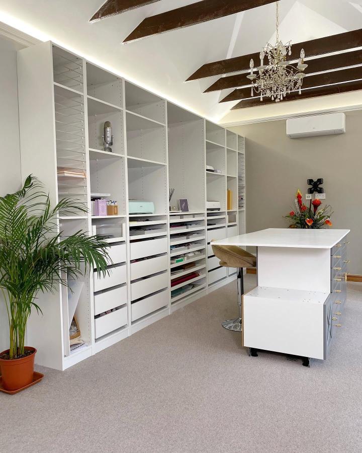 White modular storage wall from @rabia.khans with organized craft paper and modern workspace setup.