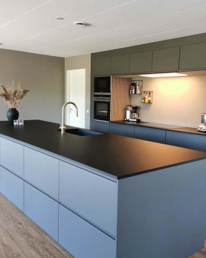 Matte grey island with black countertop from @nataschacentio featuring sage upper cabinets and wood slat detail.