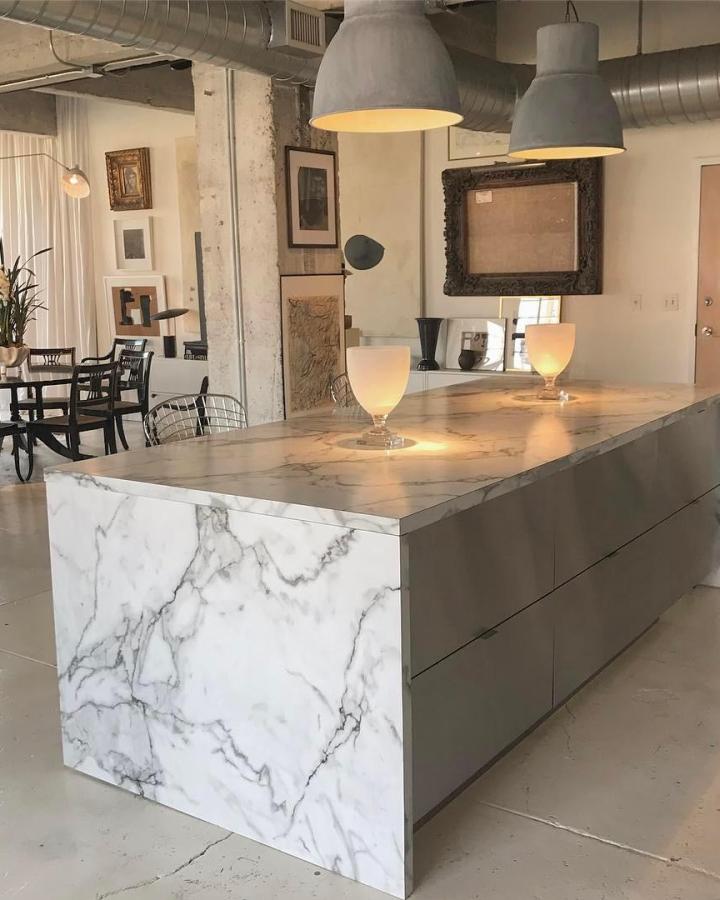 White marble waterfall kitchen island from @william_mclure with grey Metod cabinets in industrial loft setting.