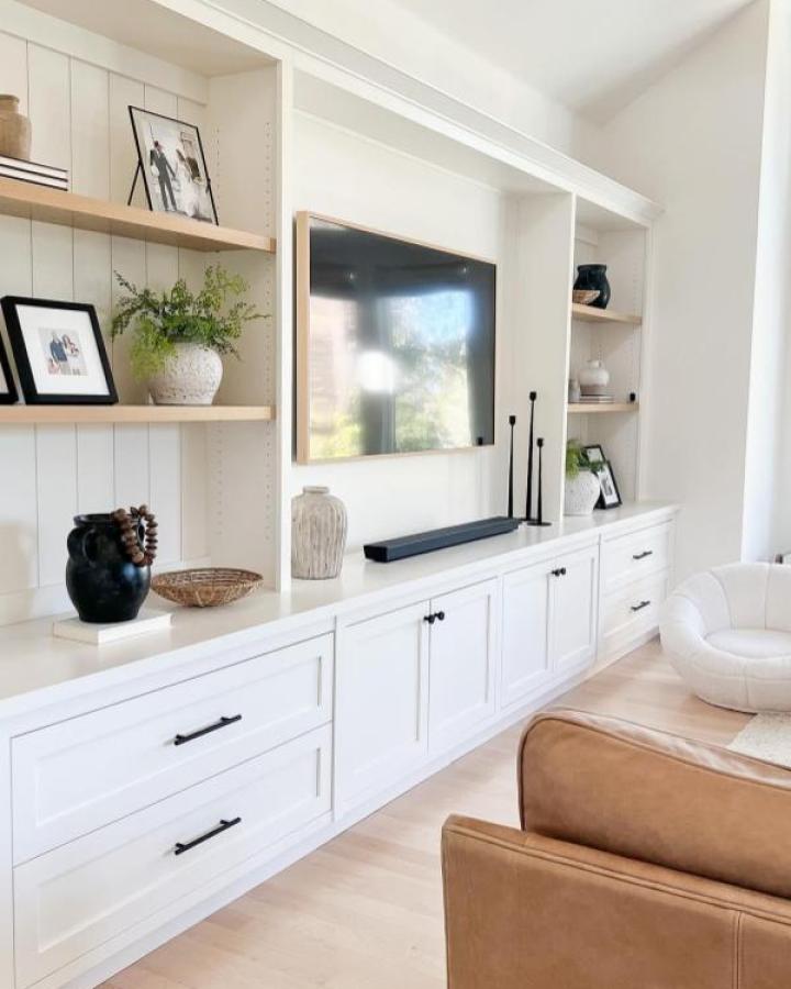White built-in media wall from @eyeforpretty with light wood shelves and black hardware accents.