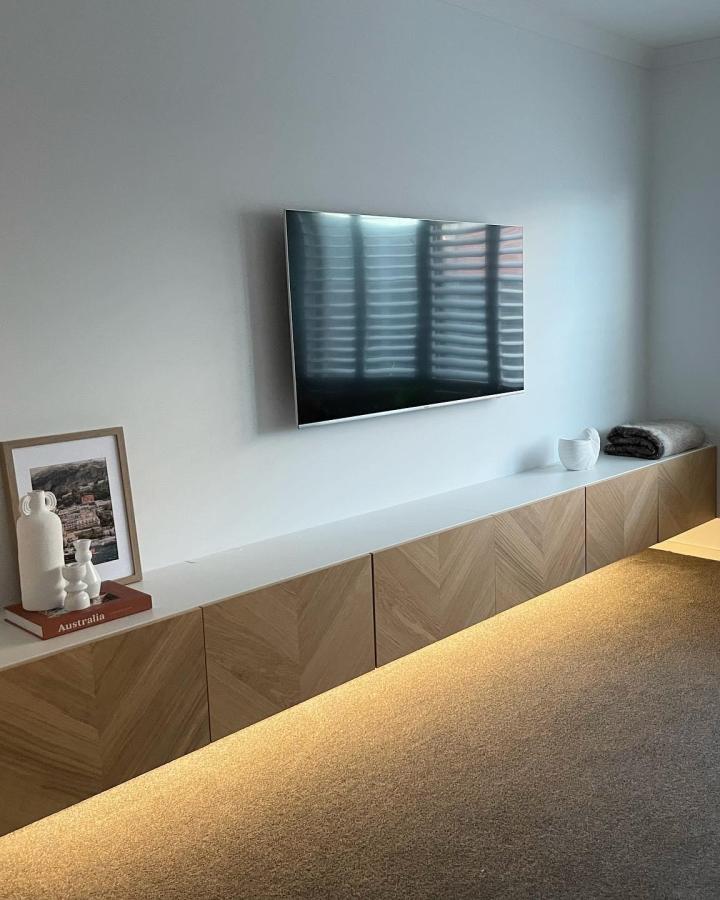 Herringbone oak media console from @thejettynorthbuild. Wall-mounted unit beneath flat screen television.