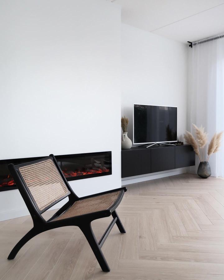 Minimalist black floating media console from @byhilalorhan with fireplace and neutral decor accents.