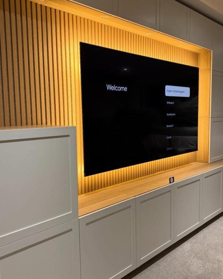 Natural wood slatted media wall from @theflatpackmanni. Gray Besta cabinets with backlit TV niche.