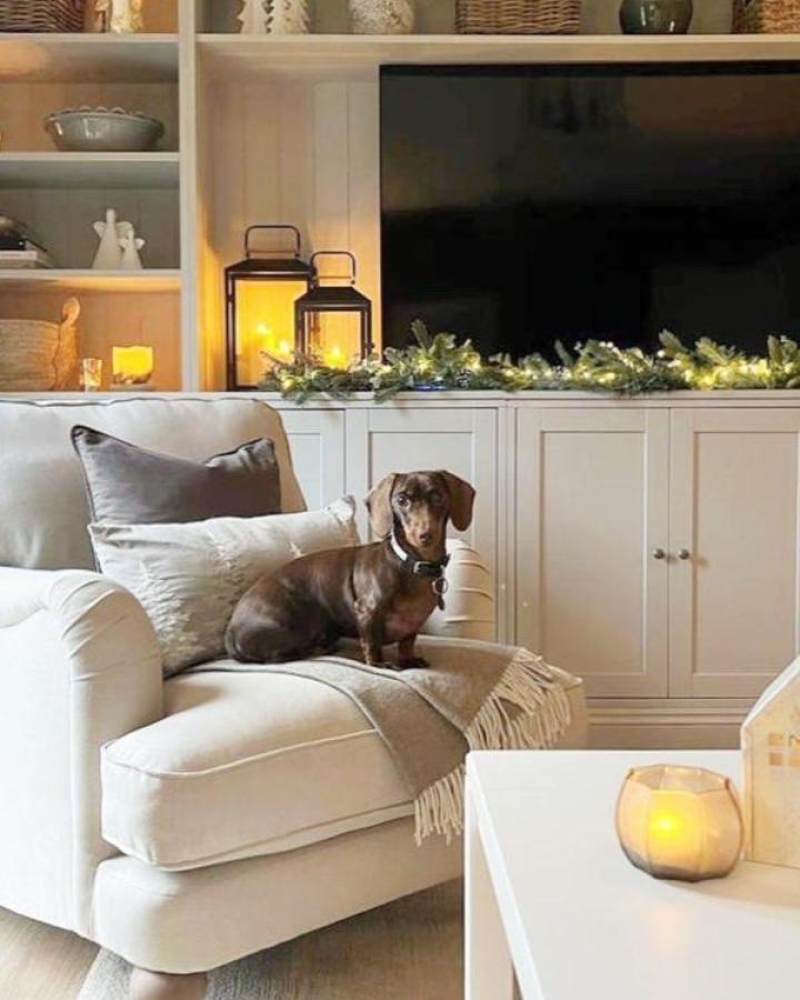 White Billy media console from @grace.athome styled with evergreen garland and glowing lanterns for seasonal charm.