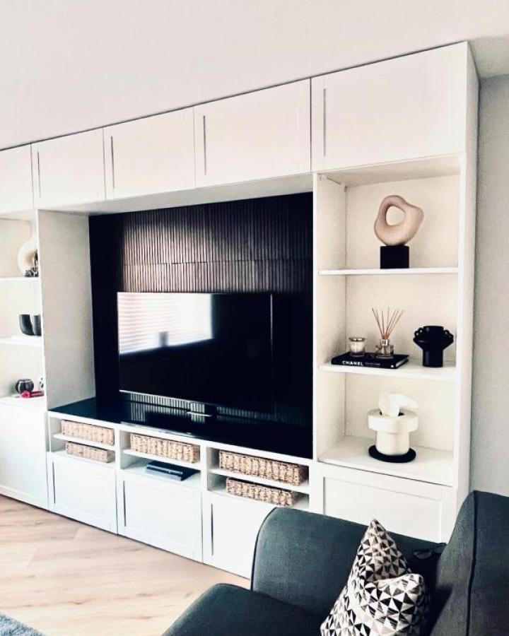 White built-in media wall unit from @our_persimmon_hatfield_plot132 with black TV backdrop and basket storage.