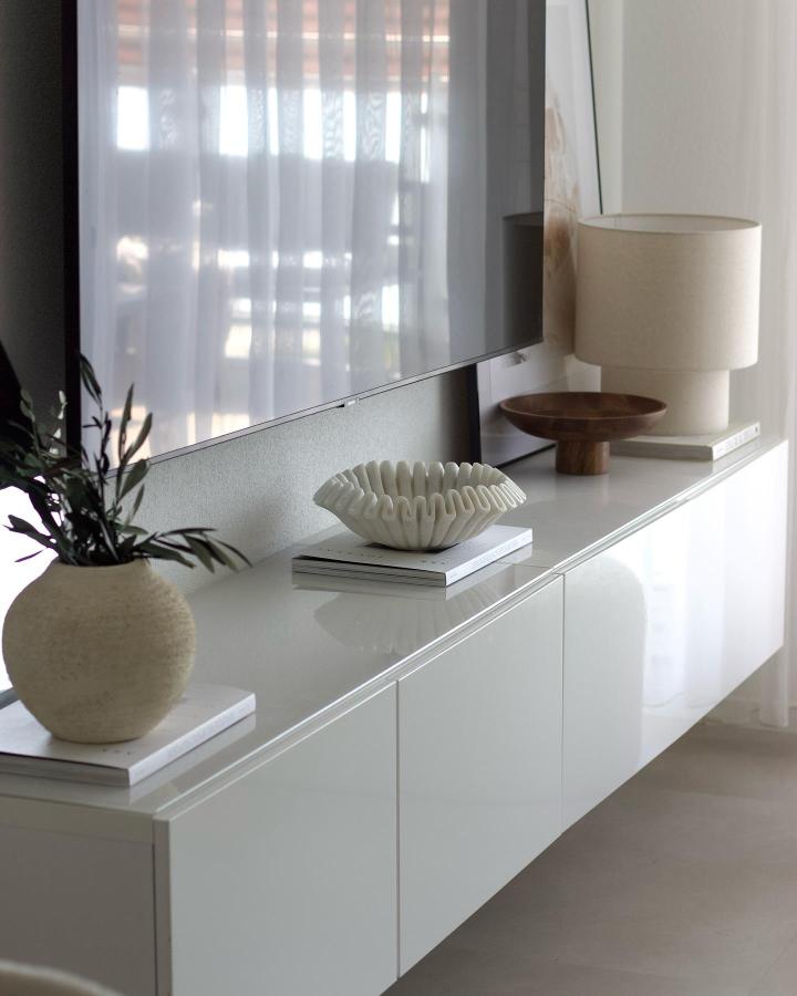 White glossy Besta media console from @interior.caaat with sculptural decor and natural light.
