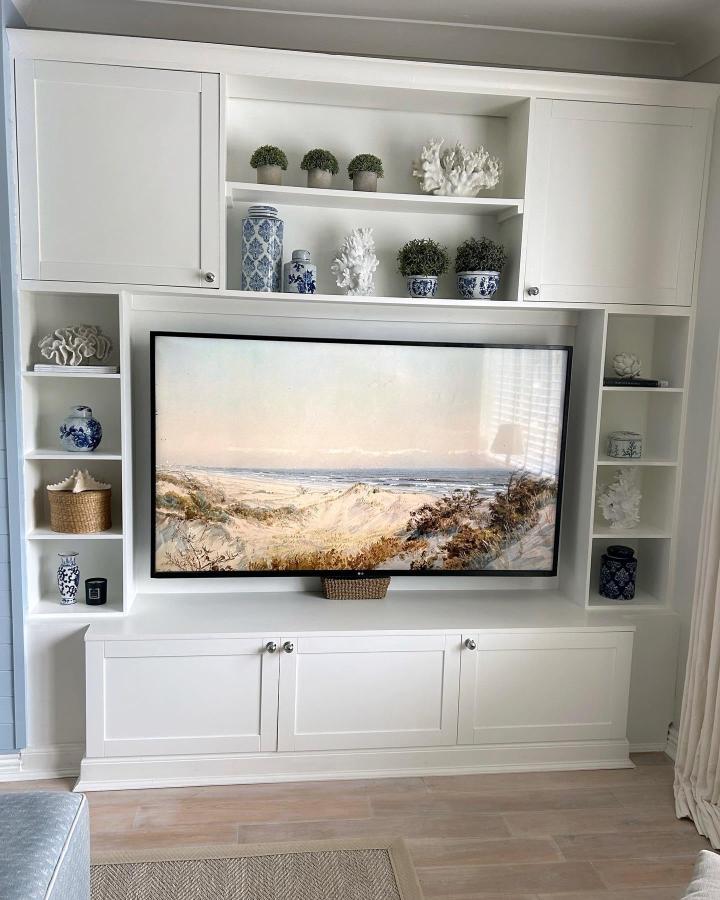 White built-in media center from @dreah.home. Coastal decor with blue ceramics and coral accents.