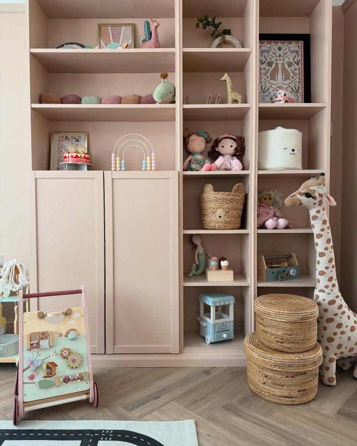 Blush pink Billy bookcase from @thehouseof_rae displaying toys, baskets, and decorative items in organized cubbies.